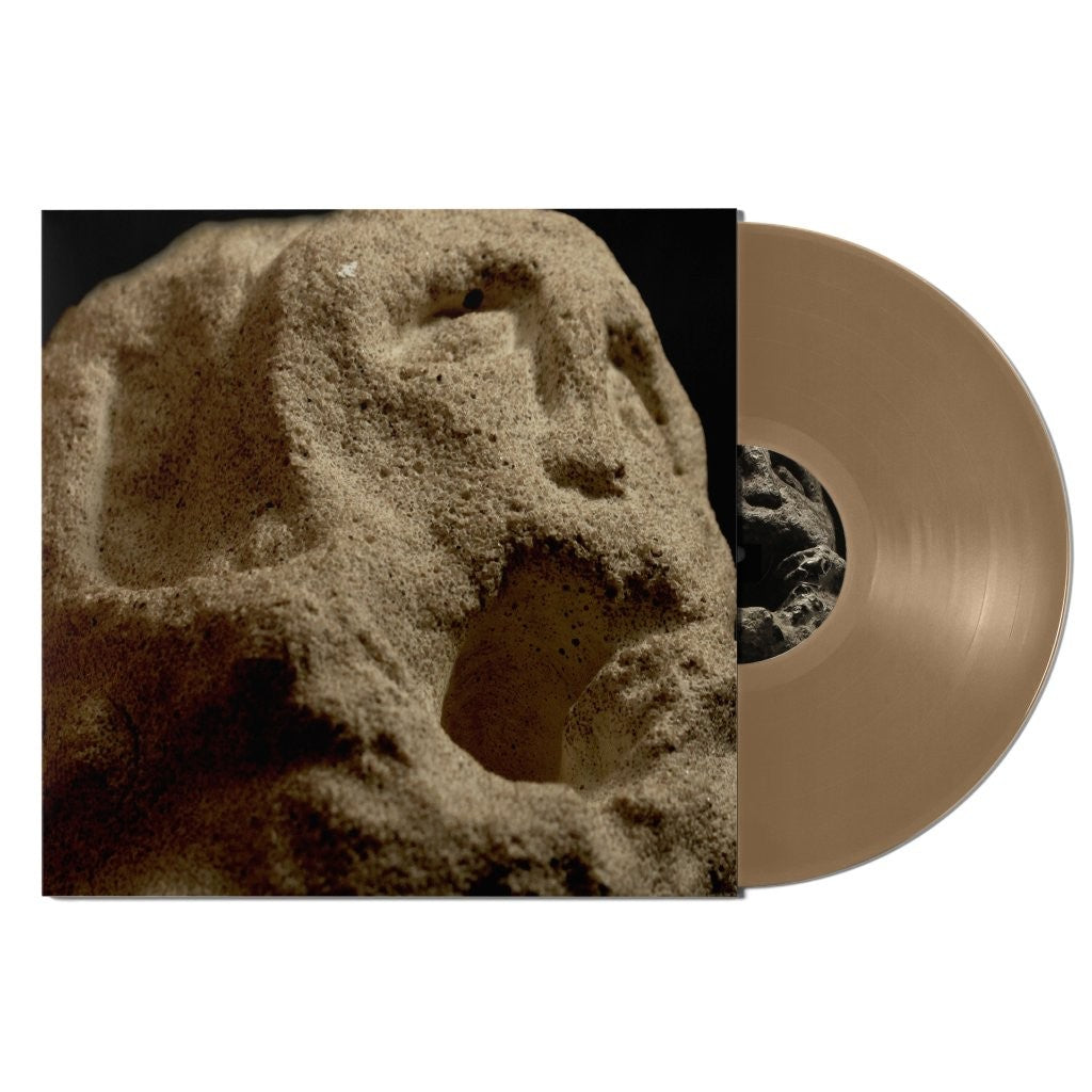 Stone carved face on album cover next to brown vinyl record.