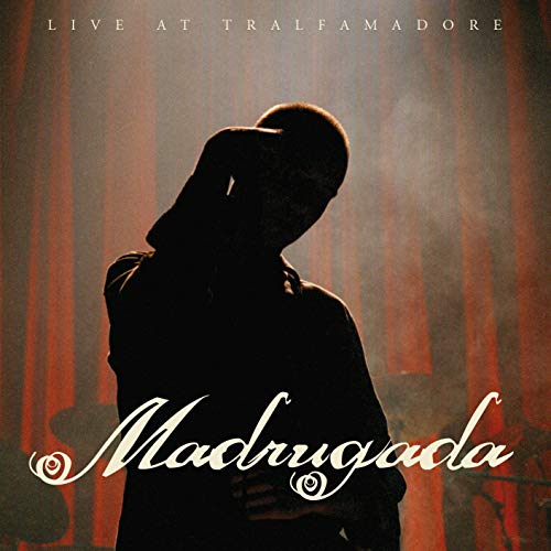 Silhouette of a person on stage against red curtains with the text Madrugada above.