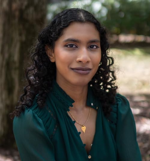 Close-up portrait of a young woman with curly dark hair and green clothing.