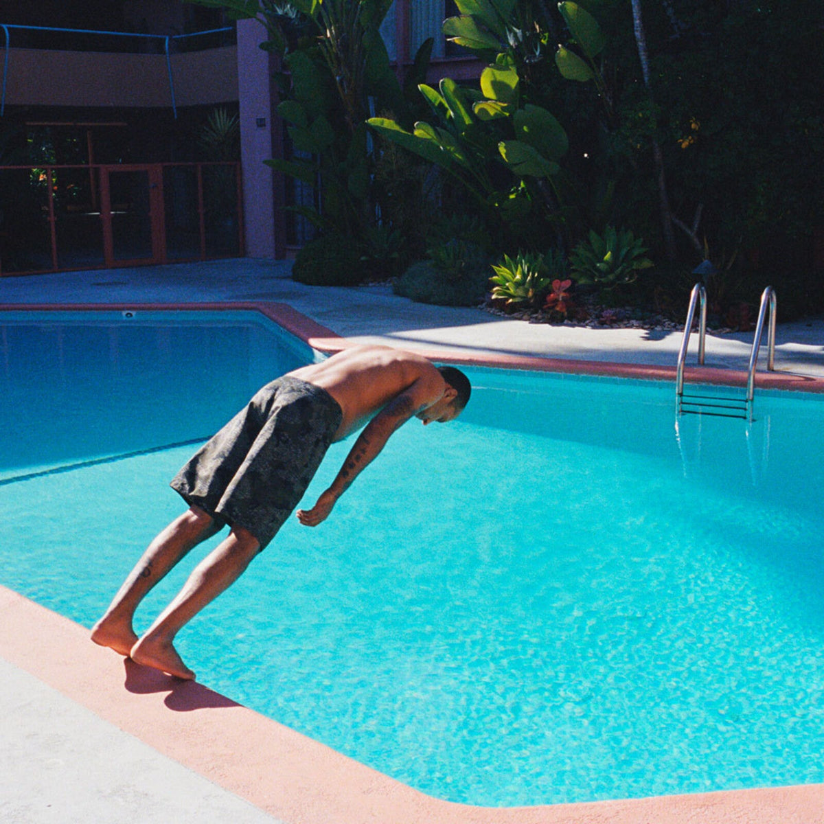 Man diving headfirst into a bright blue swimming pool.