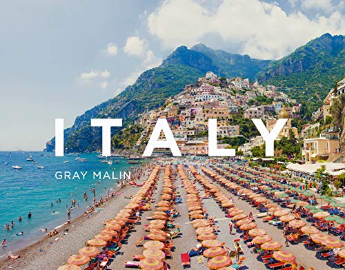 Italian coastal town with colorful buildings, beach umbrellas, and blue water.