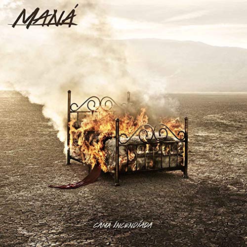 A bed frame on fire in a dry, cracked desert landscape.