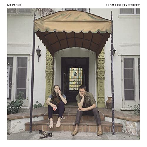 Two people sit on steps under a decorative awning, album cover.