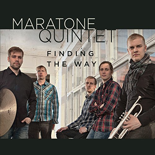 Five musicians with instruments pose in front of a blurred building.