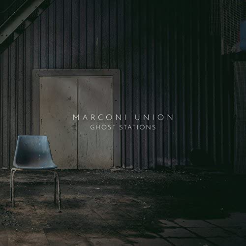Album cover: a chair before a metal wall with a closed door.