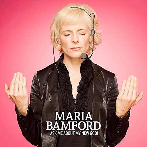 Maria Bamford wearing a headset with eyes closed against a vibrant pink background.