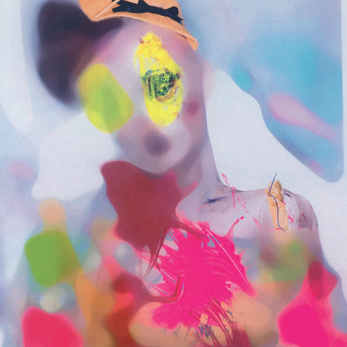A woman with colorful paint splatters on her face and body, wearing a hat.