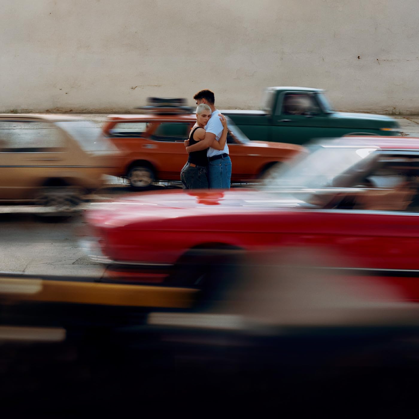 Couple embracing, blurred motion of cars in the background.