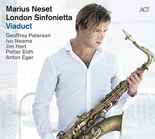 Man holding a saxophone, wearing a white shirt, on a light background.