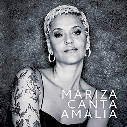 Black and white portrait of a woman with short hair and tattoos on her arm.