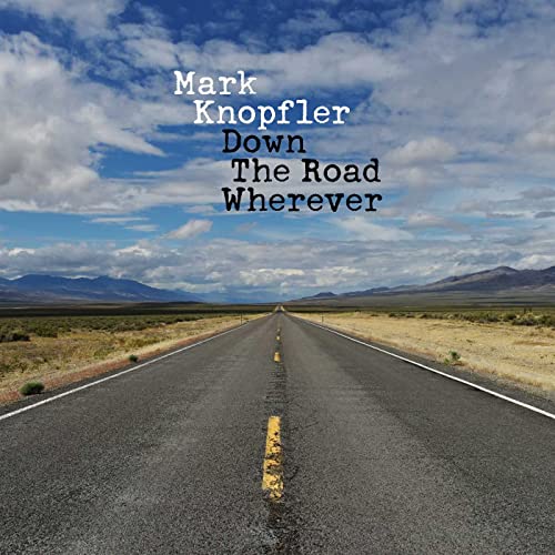 A straight road stretches toward the horizon under a blue sky with scattered clouds.