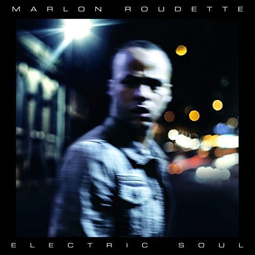 "Album cover with a man in a denim shirt against a blurred cityscape background."