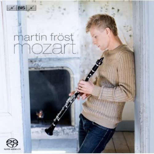 Martin Fröst in a beige sweater holding a clarinet, leaning against a doorway.