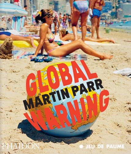 A beach ball with a world map sits on sand before sunbathers at the beach.