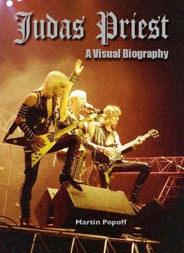 Judas Priest band members performing live on stage with guitars under warm stage lighting.