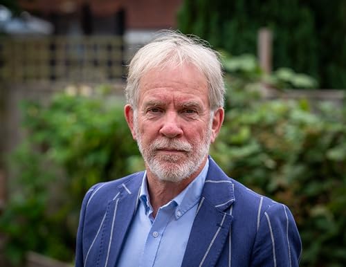 A middle-aged man with gray hair and a beard wearing a blue striped blazer.