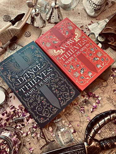 Two books, “Dance of Thieves” and “Vow of Thieves,” with scattered props.