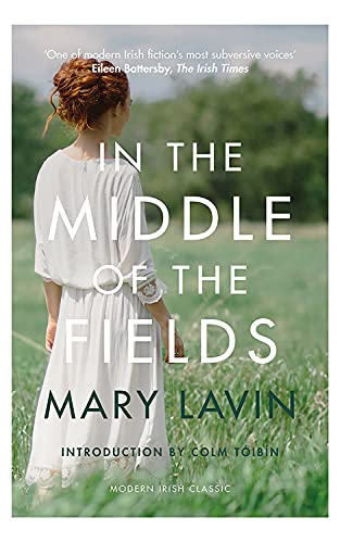 A woman with auburn hair in a white dress stands in a grassy field.