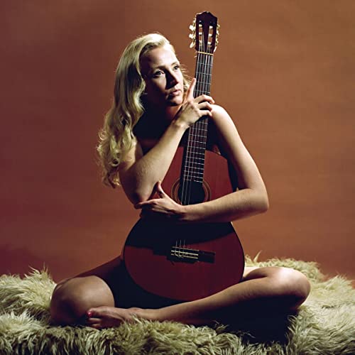 Woman with blonde hair embracing an acoustic guitar, warm tones.
