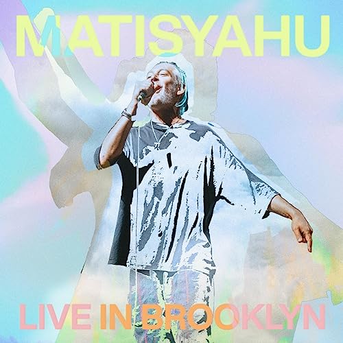 Matisyahu performing live with a blurred, colorful background.