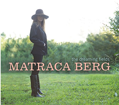 Album cover: woman in black outfit and hat standing in a green field.