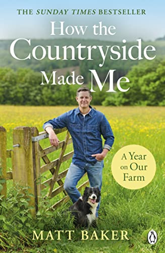Matt Baker stands in a field next to a wooden gate with a dog.