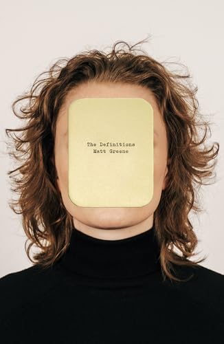 A person with wavy brown hair wears a black turtleneck with a yellow card covering their face.
