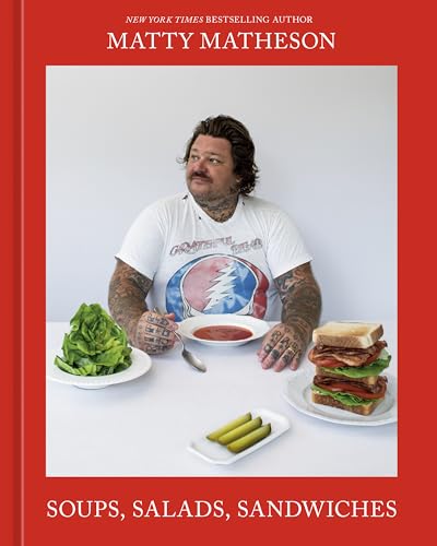 Matty Matheson sits at a table with soup, salad, a sandwich, and pickles.