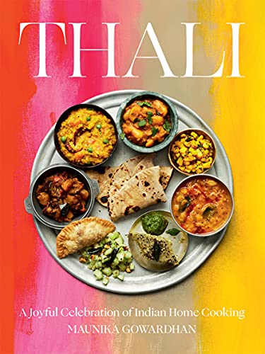 A metal tray filled with various Indian dishes and flatbreads on a colorful background.
