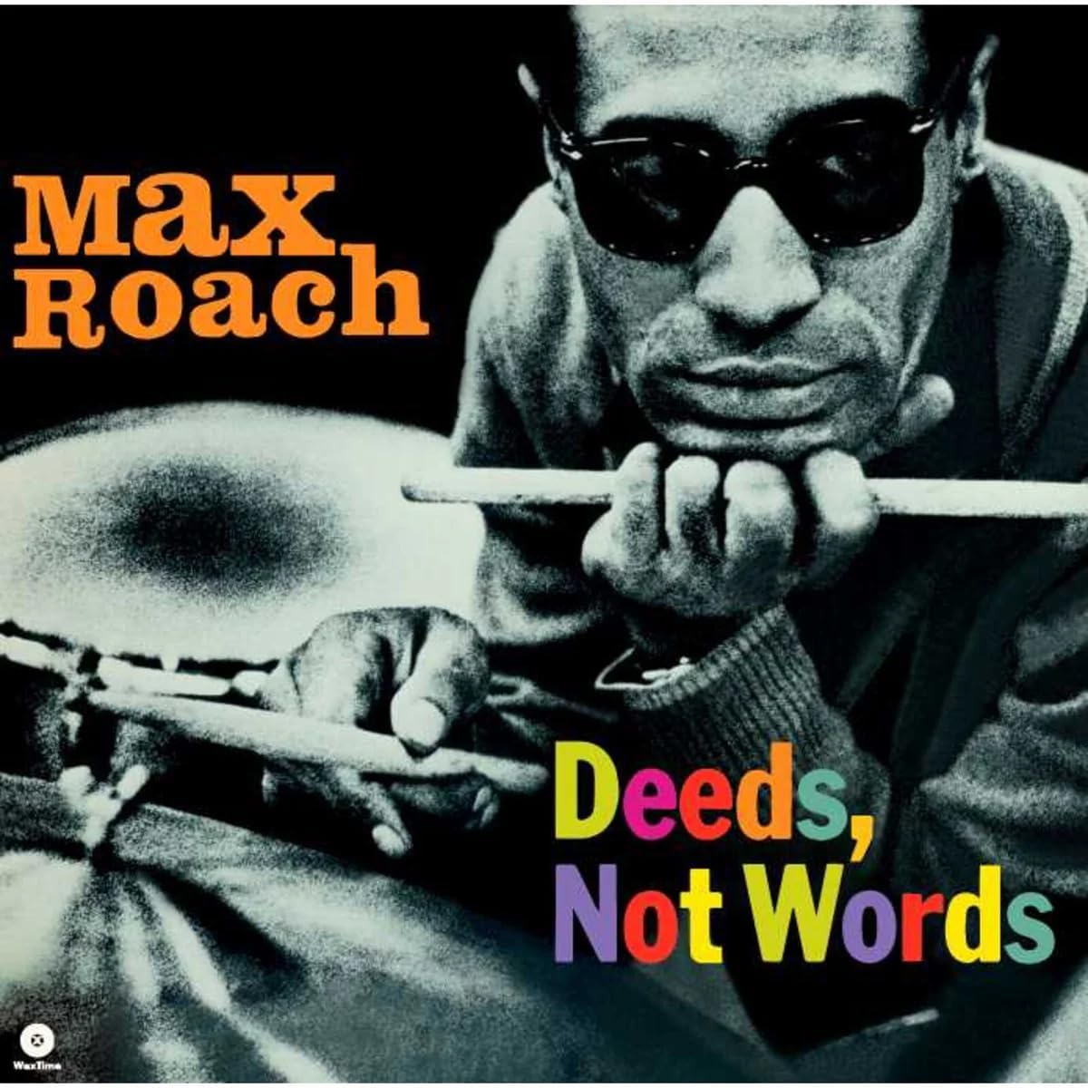 Black and white portrait of Max Roach wearing sunglasses and holding drumsticks near drums.