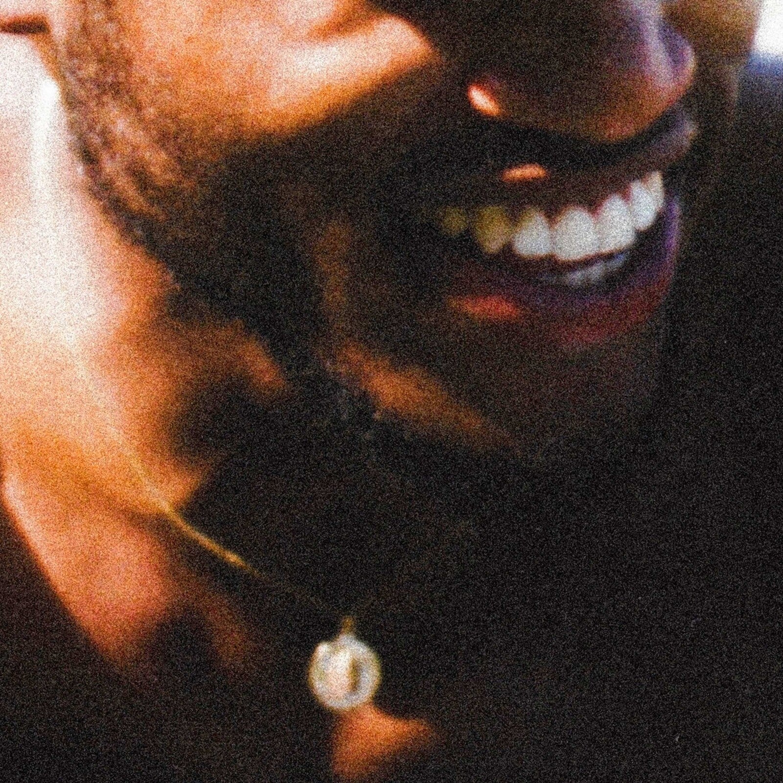 Close-up of a smiling person with gold teeth and a necklace.
