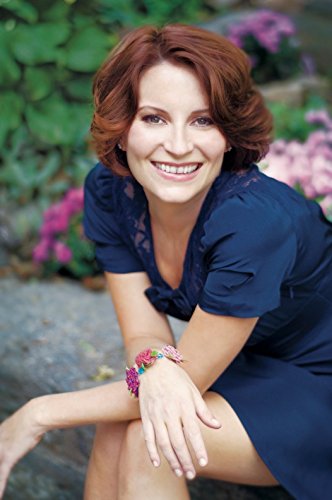 Smiling woman with red hair wearing a blue dress and floral bracelet.