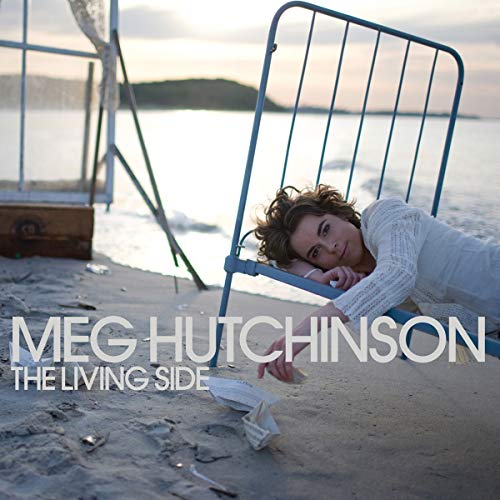Woman resting on a metal chair on a sandy beach.