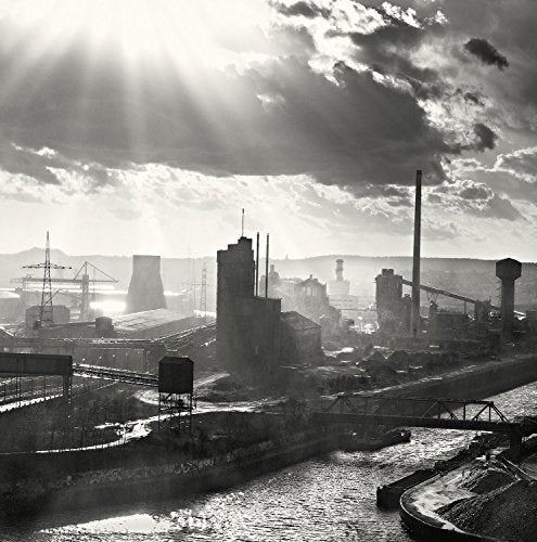 Black and white industrial landscape with smokestacks and dramatic sky.