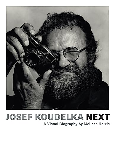 Black and white portrait of photographer Josef Koudelka holding a camera.
