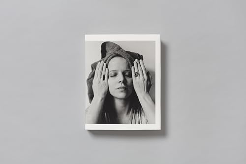 Black and white portrait of a woman with hands on her head.