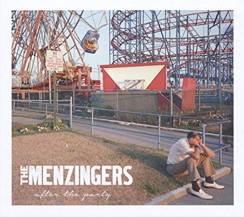 A man sits slumped on the grass in front of an amusement park ride.