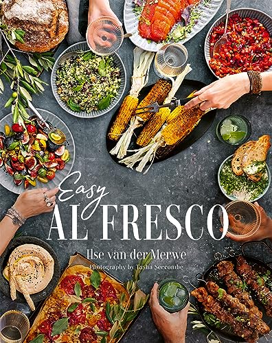 Overhead view of a cookbook with colorful food and hands reaching in.
