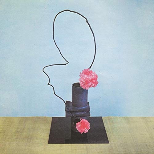 Abstract sculpture with pink flowers on stacked black geometric shapes.