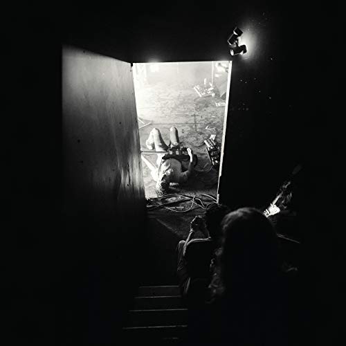 Black and white photo of a person lying on a floor, viewed through a doorway.