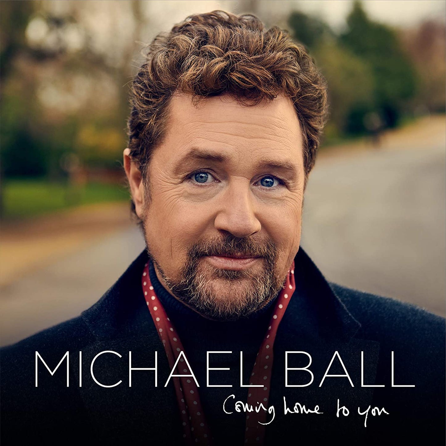 "Album cover featuring a man with curly hair and beard, outdoors."