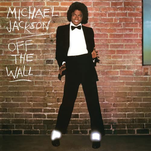 Michael Jackson in a tuxedo poses against a brick wall with album title.
