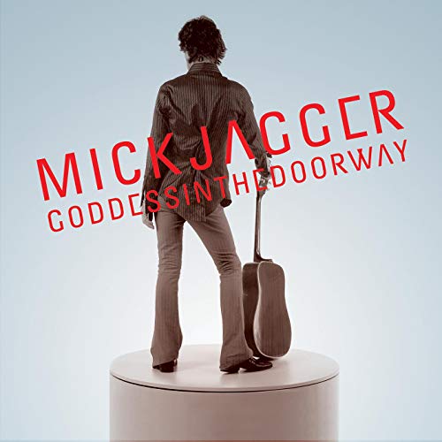 Mick Jagger standing with a guitar on a white cylindrical pedestal.