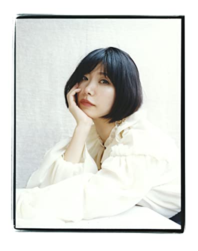 A woman with a dark bob haircut rests her chin on her hand.