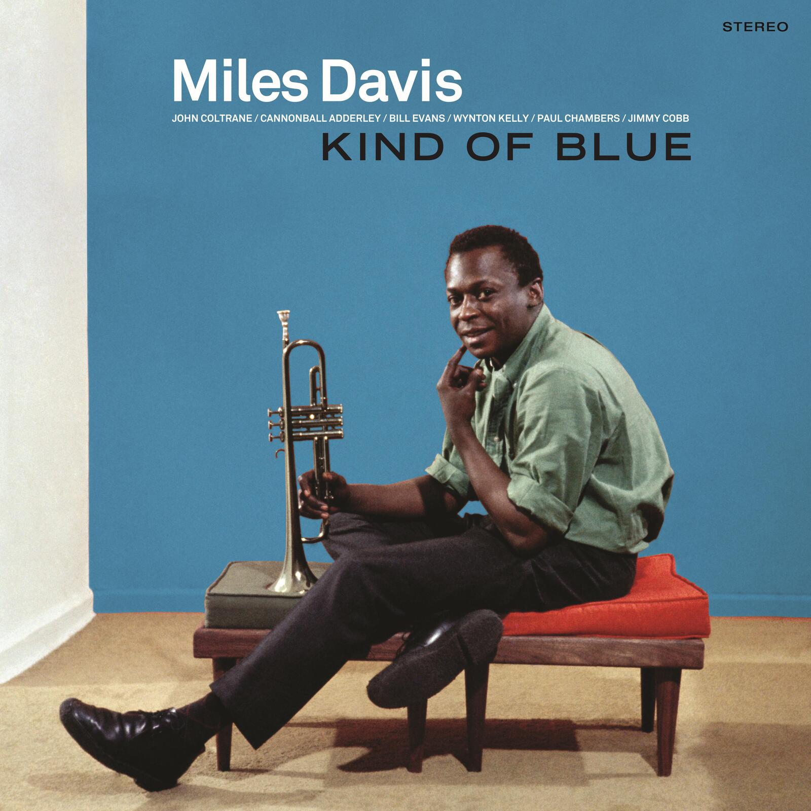 Miles Davis sits on a bench holding a trumpet against a blue background.