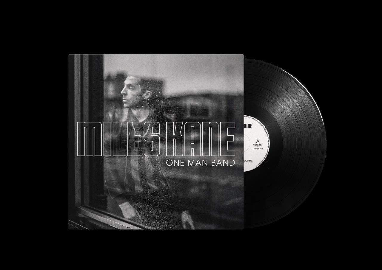 "Black vinyl record with white label and album cover featuring a man by a window."
