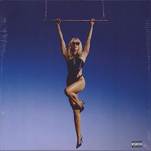 Miley Cyrus hanging from a bar against a blue sky; album cover.