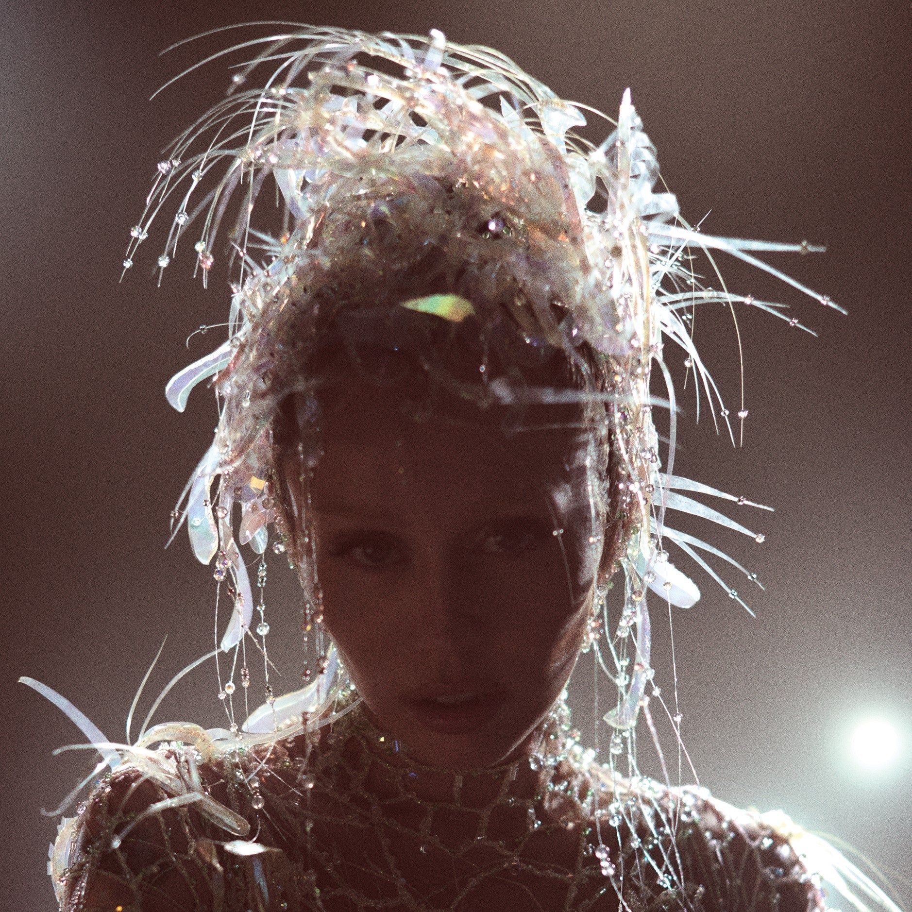 Miley Cyrus portrait with elaborate, spiky headpiece and dark lighting.