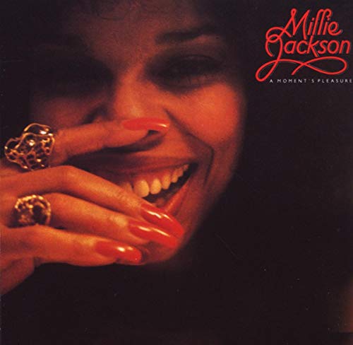 Album cover with a woman's face and hand, red nails, and ornate rings.