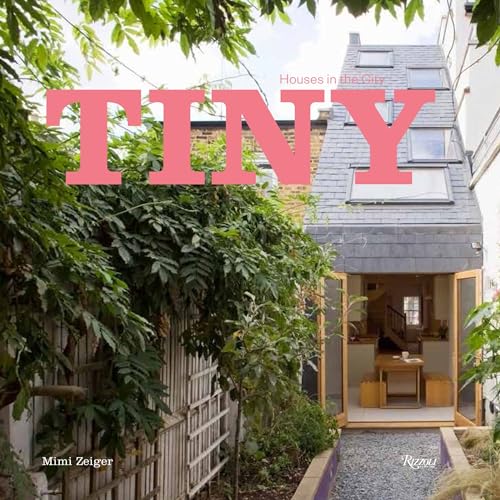 Gray tiny house with a sloped roof, framed by green foliage.